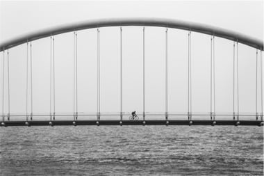 Man riding bike over bridge
